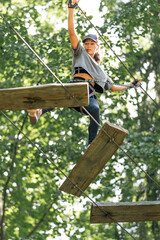 Wall Mural - a young woman challenges herself on an exhilarating outdoor ropes course, balancing on beams high ab