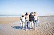 © Westend61 - Family talking while walking together at beach