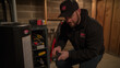 © Erzsbet - Professional Technician Inspecting a Modern Furnace in a Well-Lit Basement