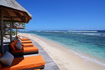Poster - Relaxing beachside loungers with orange cushions and clear blue water in a tropical setting on a sunny day