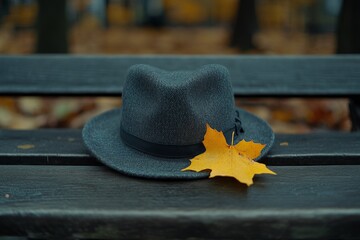 Poster - Hat rests on a wooden bench surrounded by autumn leaves in a calm park setting