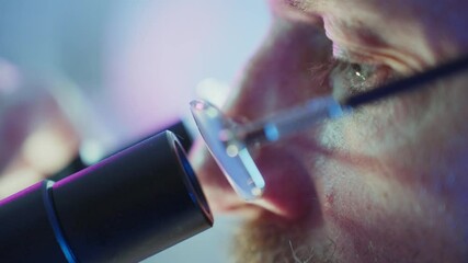Wall Mural - scientific researcher wearing glasses intently peering into microscope lens, surrounded by vibrant l