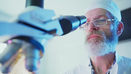 Wall Mural - professional scientist wearing lab coat examining sample through microscope in modern research labor