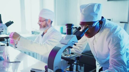 Wall Mural - medical research scientists wearing lab coats and protective glasses working with microscope and tes
