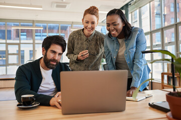Diverse group of smiling young businesspeople working on a laptop
