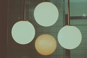 Poster - Spherical Elegance: Four spherical lamps hang gracefully, radiating a soft, warm glow, creating an atmosphere of calm sophistication in a stylish interior space.