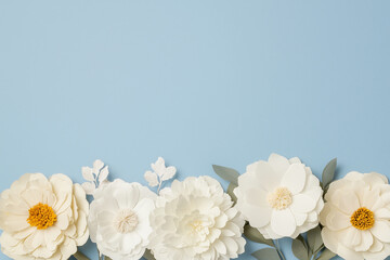 Poster - Floral Serenity: Delicate white paper flowers with yellow centers adorn a gentle blue backdrop, creating a soothing composition, inviting contemplation and artistic exploration.