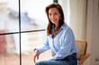 © sepy - Attractive brunette haired woman sitting on a chair in her cozy home by the window