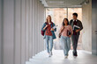 © Drazen - Happy student and her college friends walking through hallway.