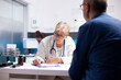 © DC Studio - Senior medic specialist using clipboard to write prescription for elderly man at checkup. Retired female doctor taking notes during medical consultation with male pensioner patient in hospital office.