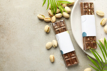 Wall Mural - delicious dubai chocolate bars, pistachios and leaves on light background, flat lay. space for text