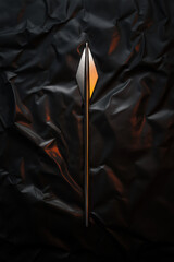 Poster - Sharp metallic arrowhead lying on dark crinkled fabric under warm light