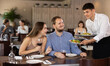 © JackF - Young guy waiter brings order from couple young man and young woman in restaurant