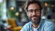 © Phurichai - Smiling man with beard wearing glasses in a bright modern living room with soft furnishings and greenery