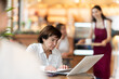 © JackF - Mature woman sitting at a table in a coffee shop and working attentively on her laptop. European pensioner is working on a laptop in a cafe