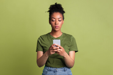 Gadget Addiction Concept. Portrait of serious black girl using cell phone on green studio background