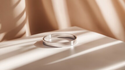 Poster - A close-up of a shiny silver cuff bracelet resting on a neutral-colored surface with clean space for modern branding or product design.