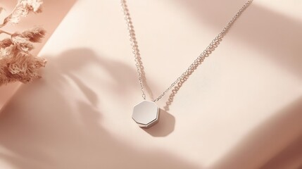 Poster - A minimalist silver necklace with a geometric pendant resting on a light-colored background, providing ample space for branding.