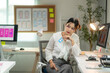 © Wasana - A woman sits at a desk with a blue card in her hand