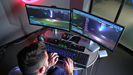 A professional gamer is programming a video game. He is typing on the keyboard, and the screen shows code and a video game