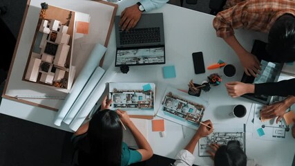 Poster - top view of smart architect engineer writing at blueprint while sitting at meeting table with house 