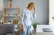© Studio Romantic - Overworked adult woman suffering from severe headache or migraine, touching forehead, feeling tired after working long hours at computer, standing near desk in living room, having health problems