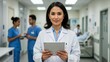 © Qbertstudio - Hispanic female doctor in white coat holding tablet in hospital corridor Healthcare teamwork, diversity focus