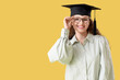 © Pixel-Shot - Happy female student in graduation hat on yellow background