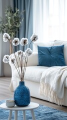 Poster - A beautifully arranged living room features a blue vase with cotton flowers, enhancing the tranquil atmosphere. Soft colors and natural light create a cozy, inviting space perfect for relaxation