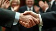 © Abdul - Close-Up of Two Businesspeople Shaking Hands with Applauding Colleagues in the Background, Displaying Professionalism and Cooperation in a Corporate Environment