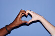 © Seventyfour - Image of interracial hands forming heart shape against blue background being illustrative of unity, love, and solidarity