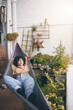 © peopleimages.com - Woman, relax and lying with hammock in garden for morning, fresh air or peaceful nap at home. Female person, comfort or hanging bed with plants on balcony for rest, break or calming zen at house