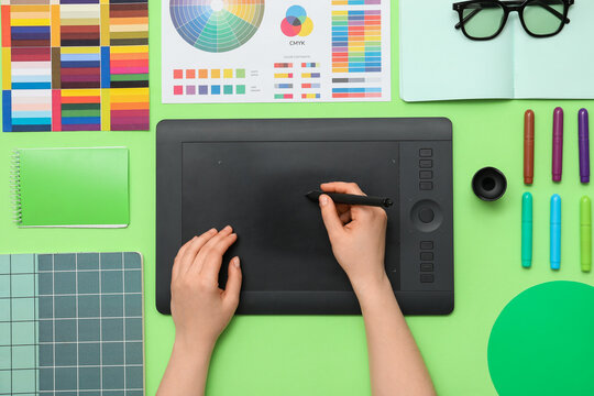Female graphic designer working with tablet on green background, top view