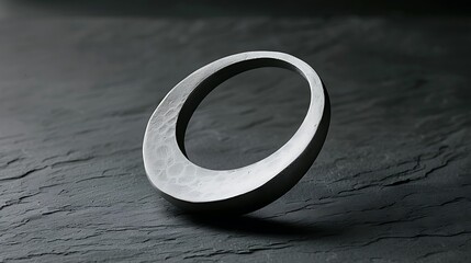 Poster - A metallic ring sculpture is placed on a textured surface