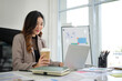 © wattana - Successful businesswoman is focused on her work, sipping coffee as she types on her laptop.
