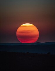 Poster - A stunning display of warmth fills the sky as the sun sets, casting vibrant hues of orange and red above rolling hills. The atmosphere radiates cosmic beauty, igniting imagination Generative AI
