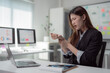 © Tj - Young Asian businesswoman is massaging her wrist while working on laptop computer in modern office, suffering from wrist pain after long working hours, experiencing office syndrome