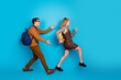 © deagreez - Young stylish couple walking against vibrant blue background, showcasing retro fashion and casual youthfulness