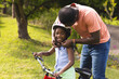 © Wavebreak Media - Father helping daughter with helmet while she smiles on bicycle outdoors