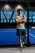 © Wavebreak Media - Young man standing confidently by padel court, wearing casual sports attire
