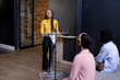 © Wavebreak Media - At office, speaking at podium, woman engaging audience, business presentation, copy space