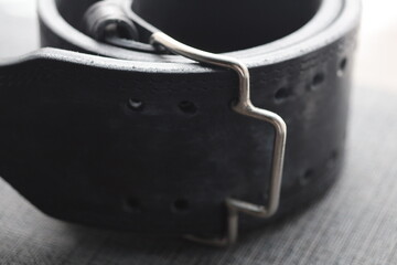 Poster - A close-up shot of a black leather belt featuring a metal buckle.