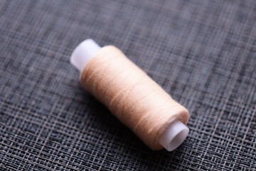 Poster - A single spool of thread sits on a table, awaiting use in sewing or crafting projects.