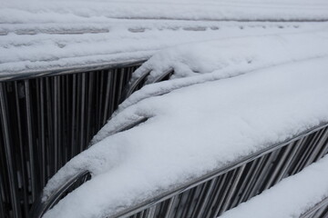 Poster - A metal fence covered in snow next to a building on a winter day.
