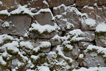 Aufkleber - A rustic stone wall covered in snow and moss.