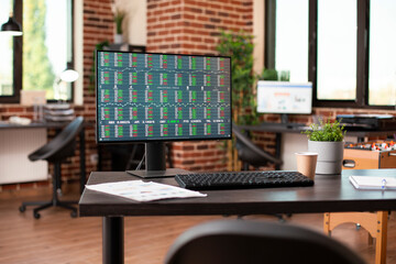 Digital display of financial stock data in vacant startup office focusing on market strategy research. Desktop monitor displaying business analytics tools, ready for use in brick wall room.