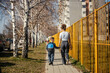 © Dusan Petkovic - Rear view of a little boy holding hands with his mom and walking on a street.
