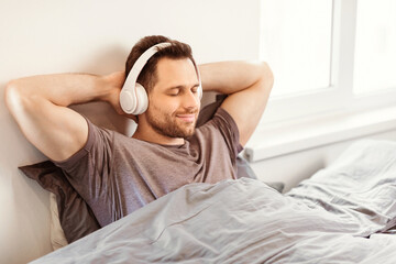 Aufkleber - Relaxed Man Listening To Music Wearing Earphones Sitting With Eyes Closed In Bed At Home. Weekend Leisure Concept
