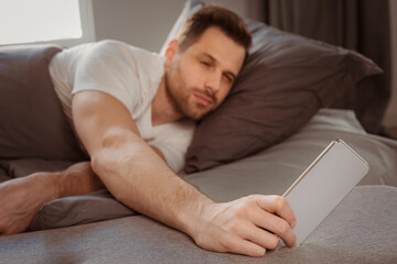 Aufkleber - Always In Touch. Man Using Smartphone Waking Up Early In The Morning Lying In Bed At Home. Selective Focus