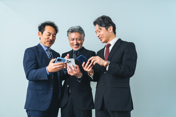 Fototapete - スマホの画面を見せ合うミドルエイジ男性ビジネスパーソンのグループ